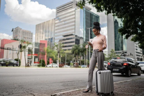 Business woman with luggage waiting for a taxi outdoors